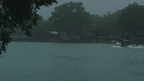 Speed boat glides through frame on the gloomy lake austin reservoir Vídeos de archivo 251226708