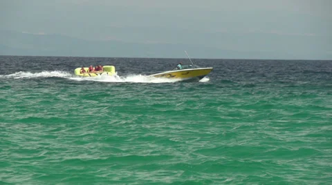 Speed boat pulling people on the rubber floater slow motion Stock Footage 32847121