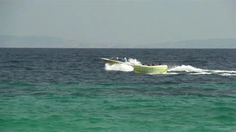 Speed boat pulling people on the rubber floater slow motion Stock Footage 32848130