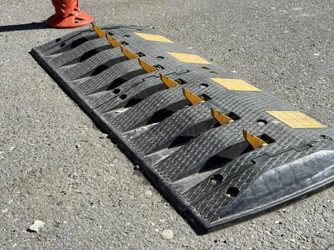 Speed bump on asphalt road with caution markings and safety elements in urb.. Stock Photos