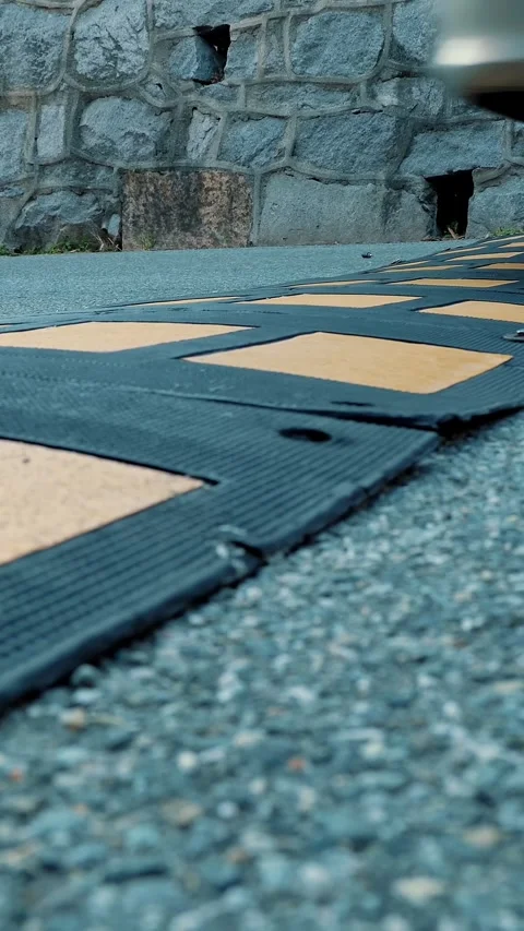 Speed bump. Close-up of car wheels. On the road, a speed bump slows down the Stock Footage 314887757