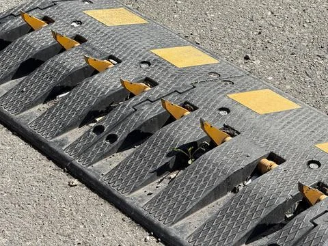 Speed bump with embedded retractable metal spikes on rough concrete road su.. Stock Photos