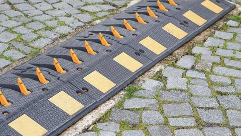 Speed bump with reflective markers on cobblestone street surface Stock Photos