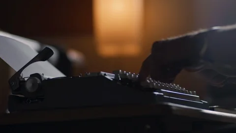 Speed ramps of a man typing at an old vintage typewriter in a moody lit office Stock Footage 97841185