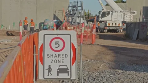 Speed sign on construction site with panel trailer, crane &amp; construction workers Stock Footage 234314778