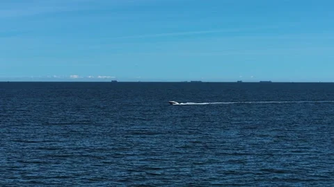 Speedboat accelerating across sea surface with tankers on horizon. Motorboat Stock Footage 319757699
