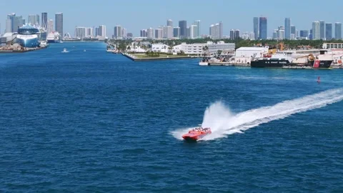 Speedboat creating spray of water while moving through ocean with city skyline Stock Footage 281937008