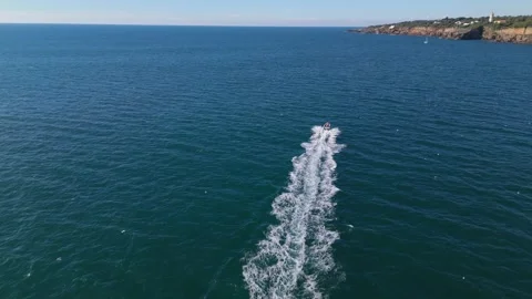 Speedboat gliding over calm waters near coastal cliffs on a sunny day Stock Footage 295269894