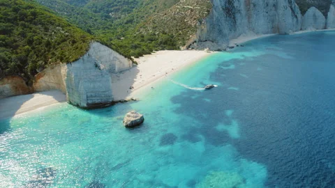 Speedboat passing near white cliffs and sandy beach with turquoise sea in Stock Footage 312177853