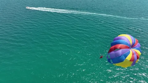 Speedboat pulling a parachute with people moving behind the boat Stock Footage 314032506