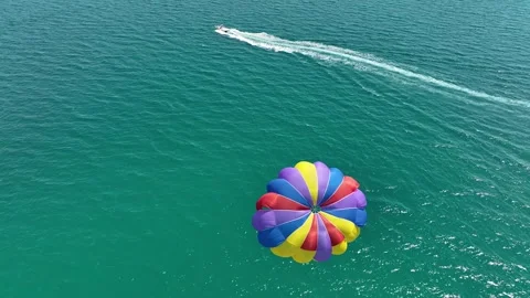 Speedboat pulling a parachute with people moving behind the boat Stock Footage 314342452