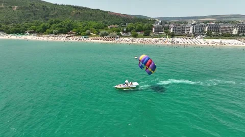 Speedboat pulling a parachute with people moving behind the boat Stock Footage 315290516