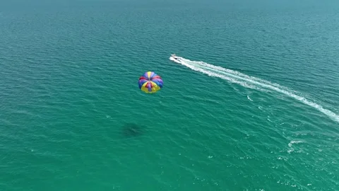 Speedboat pulling a parachute with people moving behind the boat Stock Footage 316033566