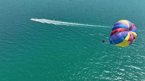 Speedboat pulling a parachute with people moving behind the boat Stock Footage 316277355