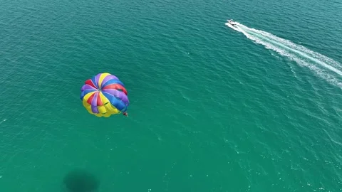 Speedboat pulling a parachute with people moving behind the boat Stock Footage 317600613