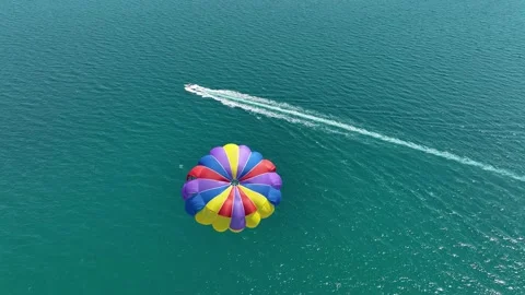 Speedboat pulling a parachute with people moving behind the boat Stock Footage 319996250