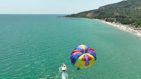 Speedboat pulling a parachute with people moving behind the boat Stock Footage 324016795