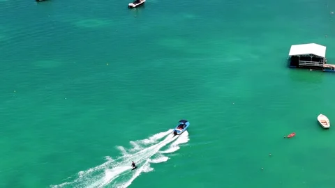 Speedboat Pulling Wakeboarder on Vibrant Turquoise Sea Stock Footage 310180651