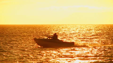 A speedboat swims, bouncing on the waves in the rays of bright sunset reflected Video stock 92205221
