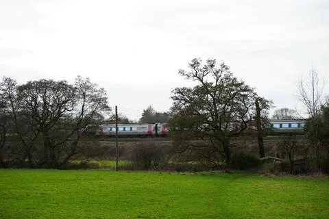 Speeding Train Through Green Field And Trees Under Cloudy Sky In Wessington, Stock Photos