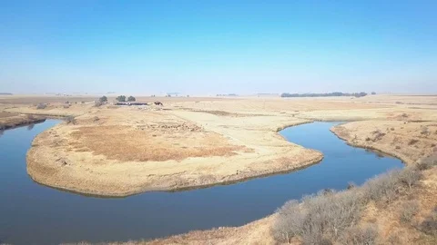 Speedy low flight over arid farmland with small river Stock Footage 79806833