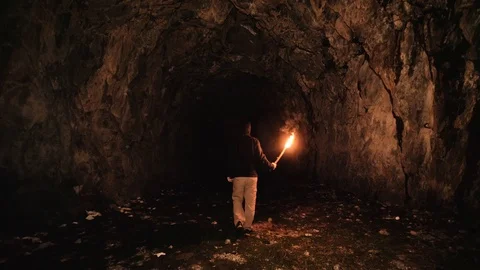 Speleologist exploring cavern with a torch Stock Footage 119393935