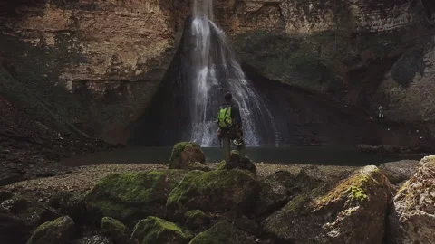 Speleologist standing in front of waterfall at the cave Stock Footage 204912631