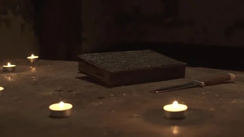 Spell book and knife lying in circle of candles on altar in gloomy basement. 스톡 동영상 245577977