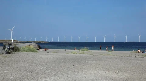 Spending time on the beach on a summerday with view to huge wind turbines at sea Stock Footage 40588099