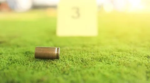 A spent bullet casing in focus, with a blurred forensic number 3 tag behind.. Stock Photos
