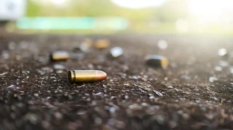 Spent bullet casing lying on dark ground with blur number 2 sign. Concepts .. Stock Photos