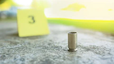 Spent bullet casing lying on dark ground with blur number 3 sign. Concepts .. Stock Photos