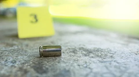 Spent bullet casing lying on dark ground with blur number 3 sign. Concepts .. Stock Photos