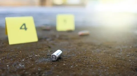 Spent bullet casing lying on dark ground with blur number 4 sign. Concepts .. Stock Photos