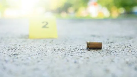 Spent bullet casing lying on dark ground with blur number 2 sign. Concepts .. Stock Photos
