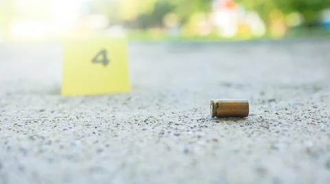 Spent bullet casing lying on dark ground with blur number 4 sign. Concepts .. Stock Photos