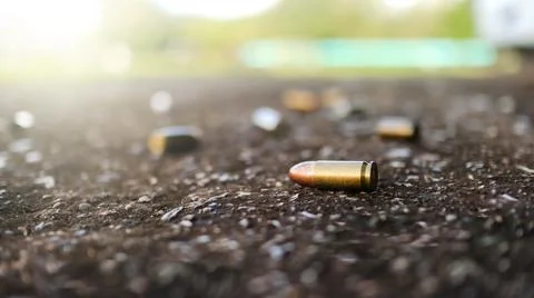 Spent bullet casing lying on dark ground with blur number 2 sign. Concepts .. Stock Photos