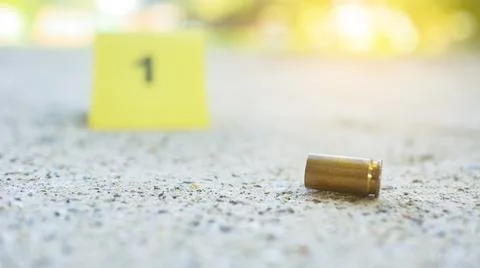 Spent bullet casing lying on dark ground with blur number 1 sign. Concepts .. Stock Photos