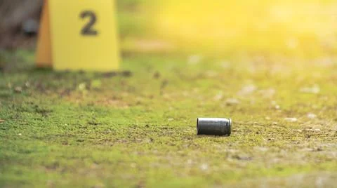 Spent bullet casing lying on the ground with blur number 2 sign. Concepts o.. Stock Photos