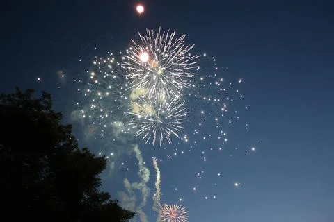Spherical fireworks display with smoke trails bursting in the night sky Stock Photos