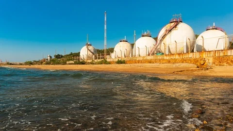 Spherical gas storage tanks in the refinery industry are on the shore with go Stock Footage 104612867