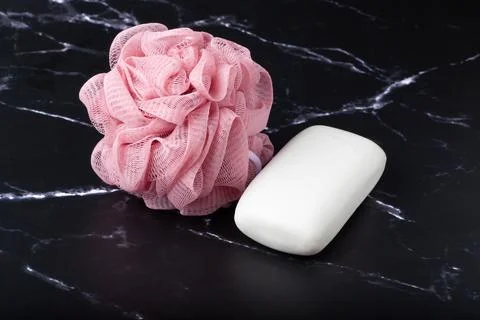 Spherical polyester bath sponge and white soap on a marble surface. Taking .. Stock Photos