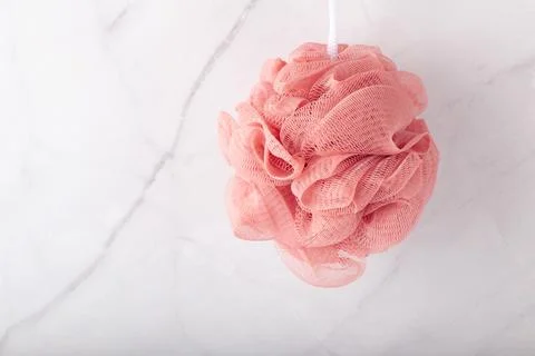 Spherical polyester bath sponge hangs on the marble wall. Stock Photos