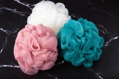 Spherical polyester bath sponges on a black marble surface. Taking bath with a Stock Photos