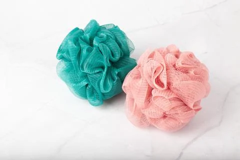 Spherical polyester bath sponges on a white marble surface. Taking bath with a Foto stock