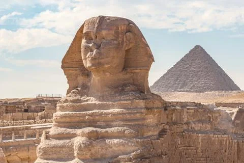 Sphinx monument against the background of large pyramids on a sunny day Stock Photos