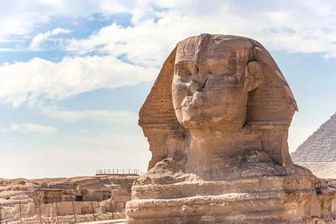 Sphinx monument against the background of large pyramids on a sunny day Stock Photos