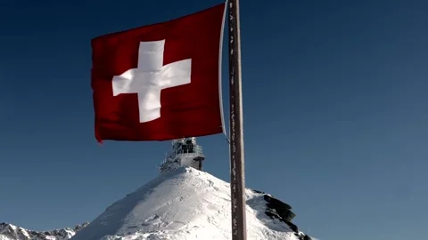 Sphinx Observatory At Top Of Jungfraujoch and Swiss Flag in a Sunny Windy Winter Stock Footage 314092479