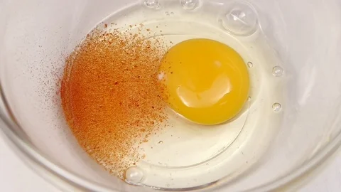 Spice pepper is added to egg. Slow motion, top view Stock Footage 76147324