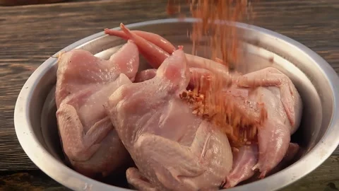 A spice rub is sprinkled on raw quail in a metal dish Stock Footage 314624899